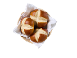 Tre kringelbullar i en flätad korg fodrad med en vit servett, ovanifrån.