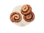 Tre kanelbullar med pärlsocker på en rund marmorbricka.