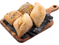 Assorterade frö- och vanliga bröd på en träskiva och mörk duk.