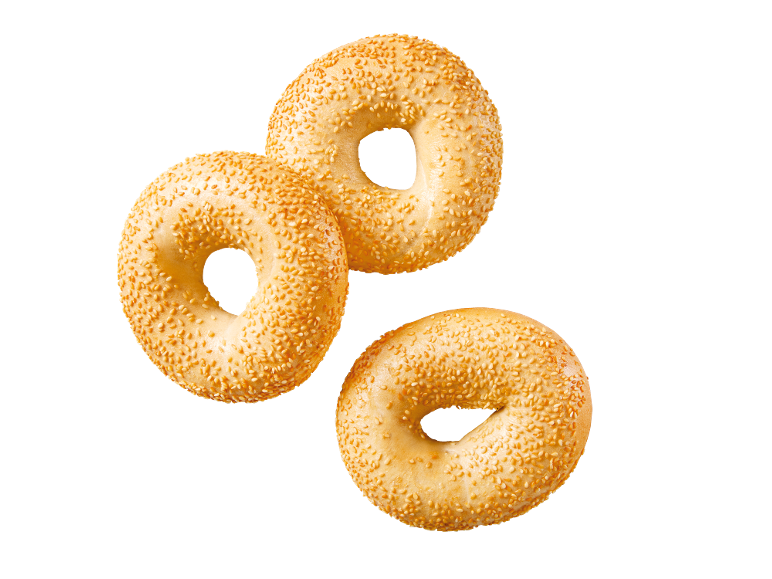 Tre gyllene sesambagels på svart bakgrund.