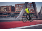 Man i reflexväst och hjälm cyklar på en röd cykelväg.