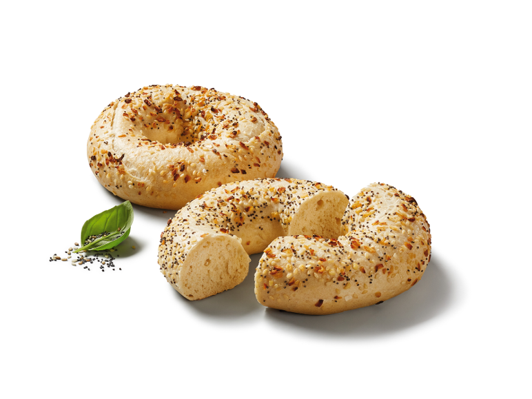 Everything bagels, en hel och en skivad, med ett basilikablad och frön.
