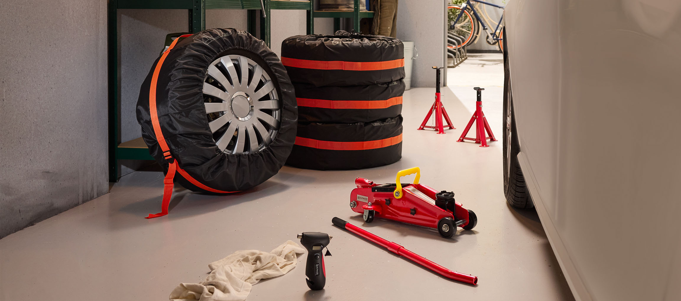 Bildäck med överdrag, domkraft och pallbockar i ett garage.