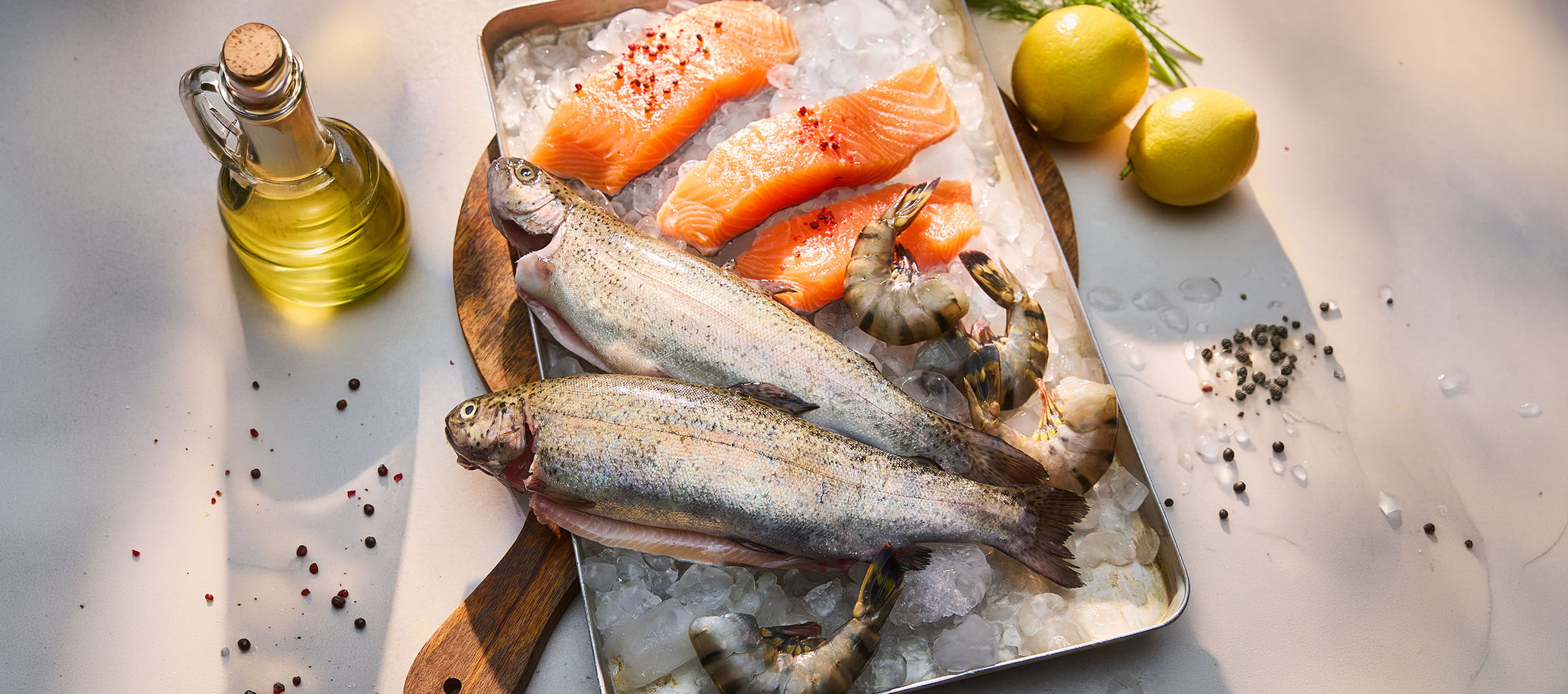 Färsk fisk och skaldjur på is, med citroner och olja.