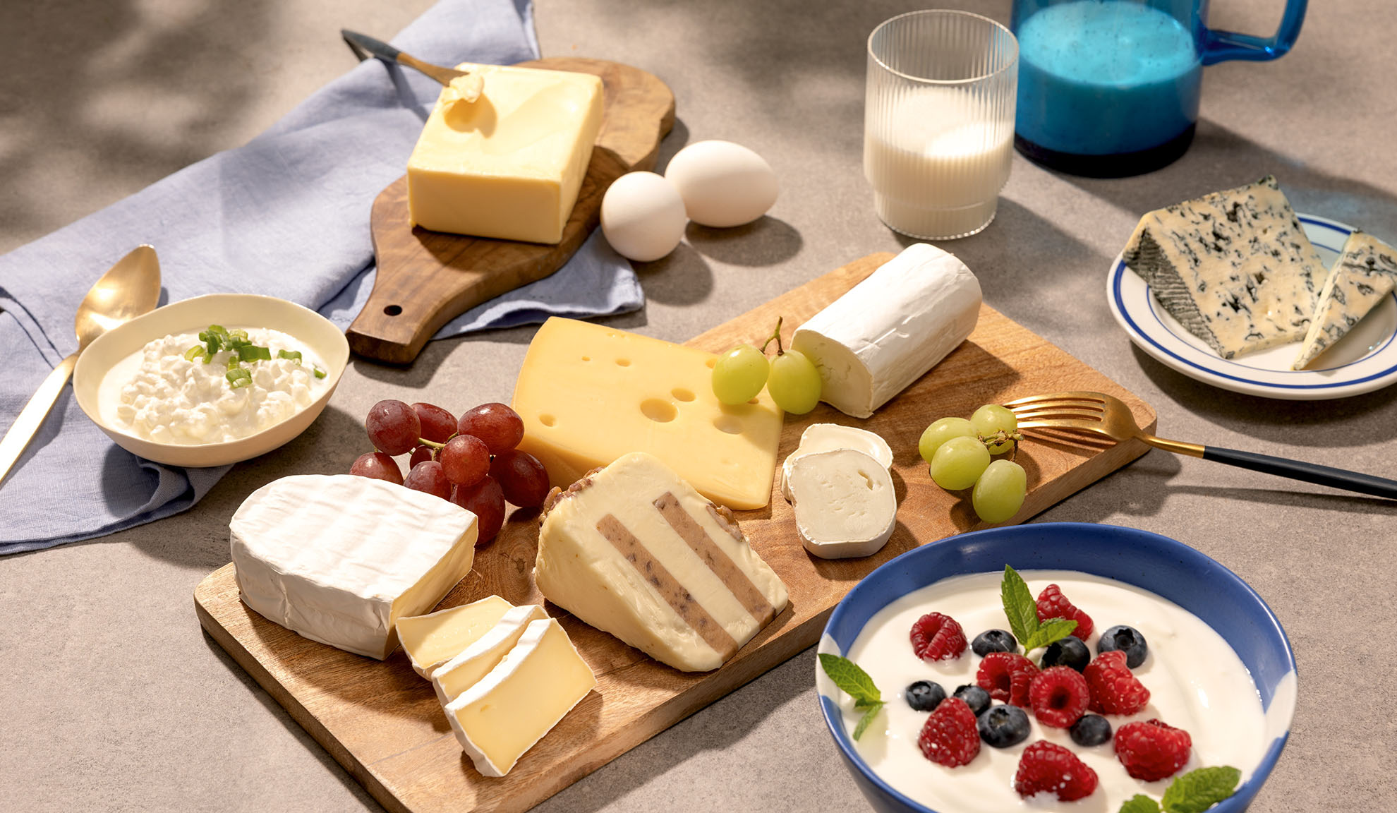 Ett urval av ostar, vindruvor och mejeriprodukter som keso, mjölk och yoghurt med bär.