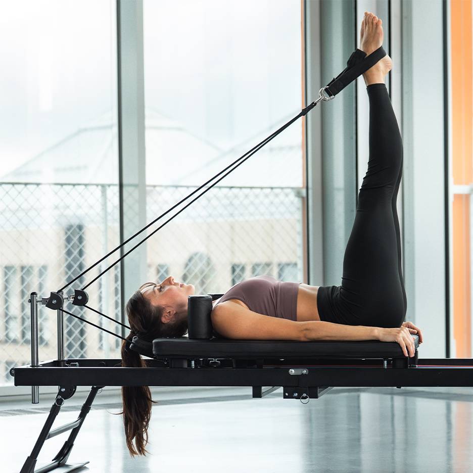 Kvinna gör benövning på en pilates reformer maskin.