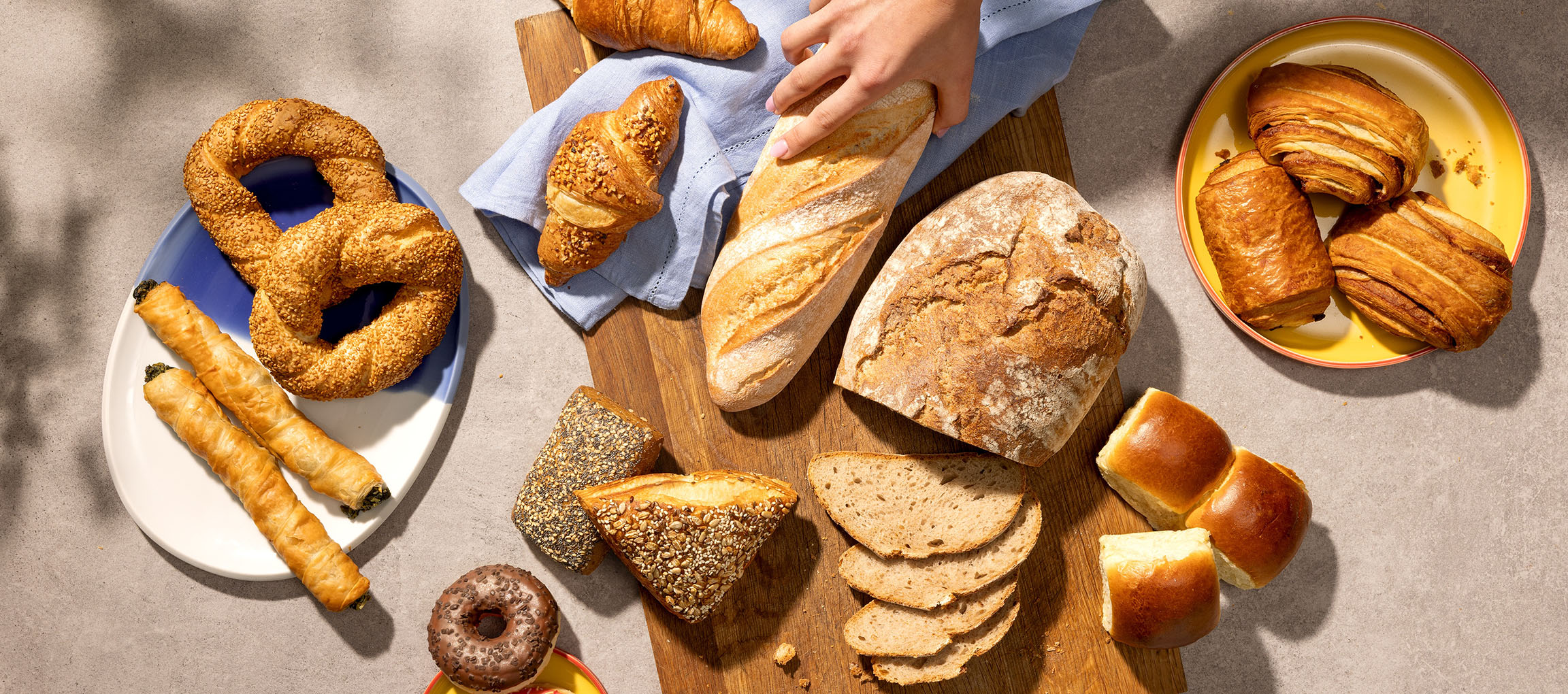 Sortiment av bakverk och bröd, inklusive kringlor, croissanter och baguetter, på ett bord.
