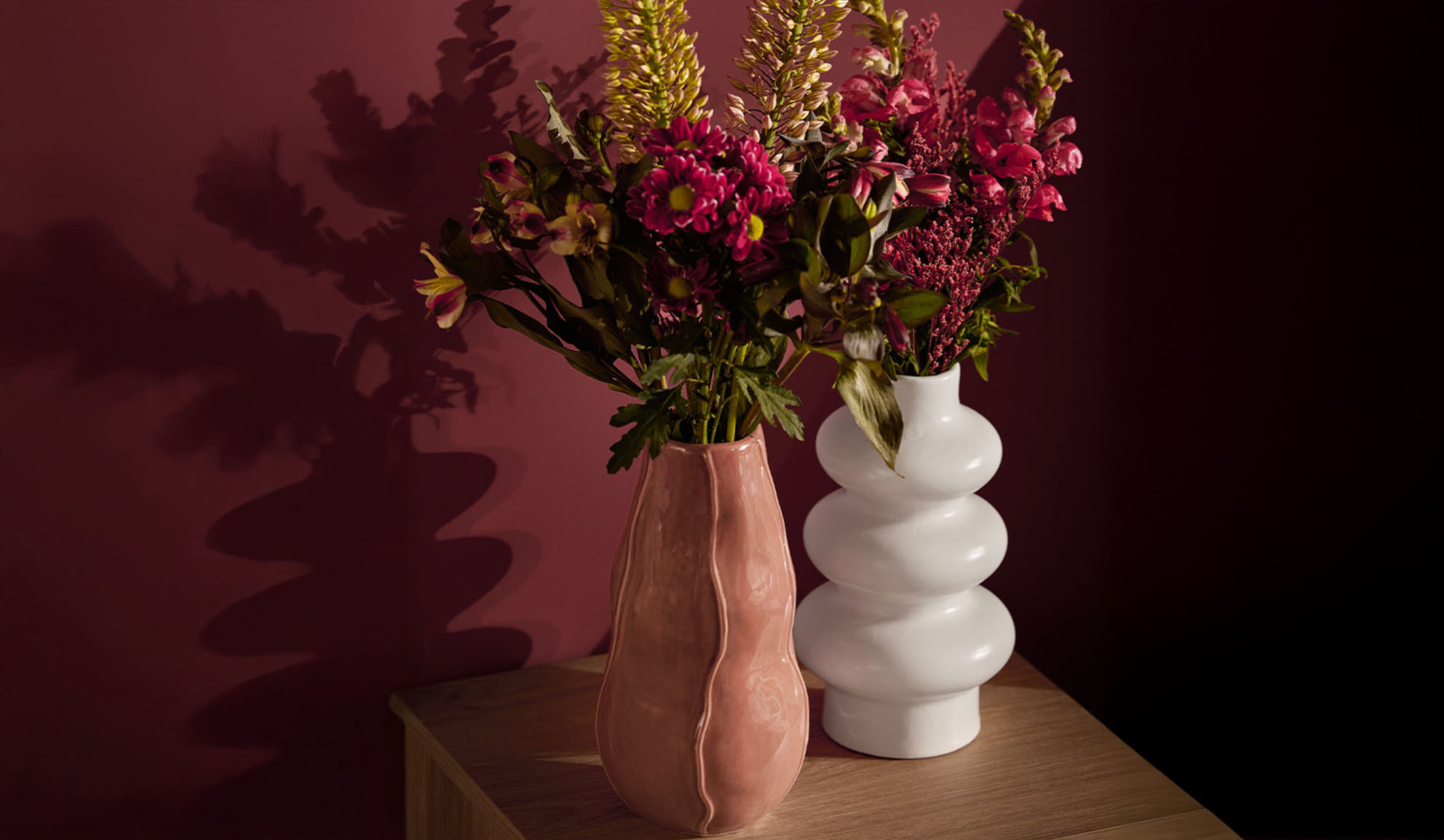 Två vaser med färgglada blommor på ett träbord.
