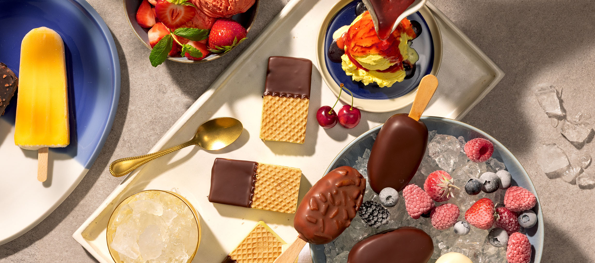Sortiment av glasspinnar, glasskulor och chokladdoppade våfflor med bär.