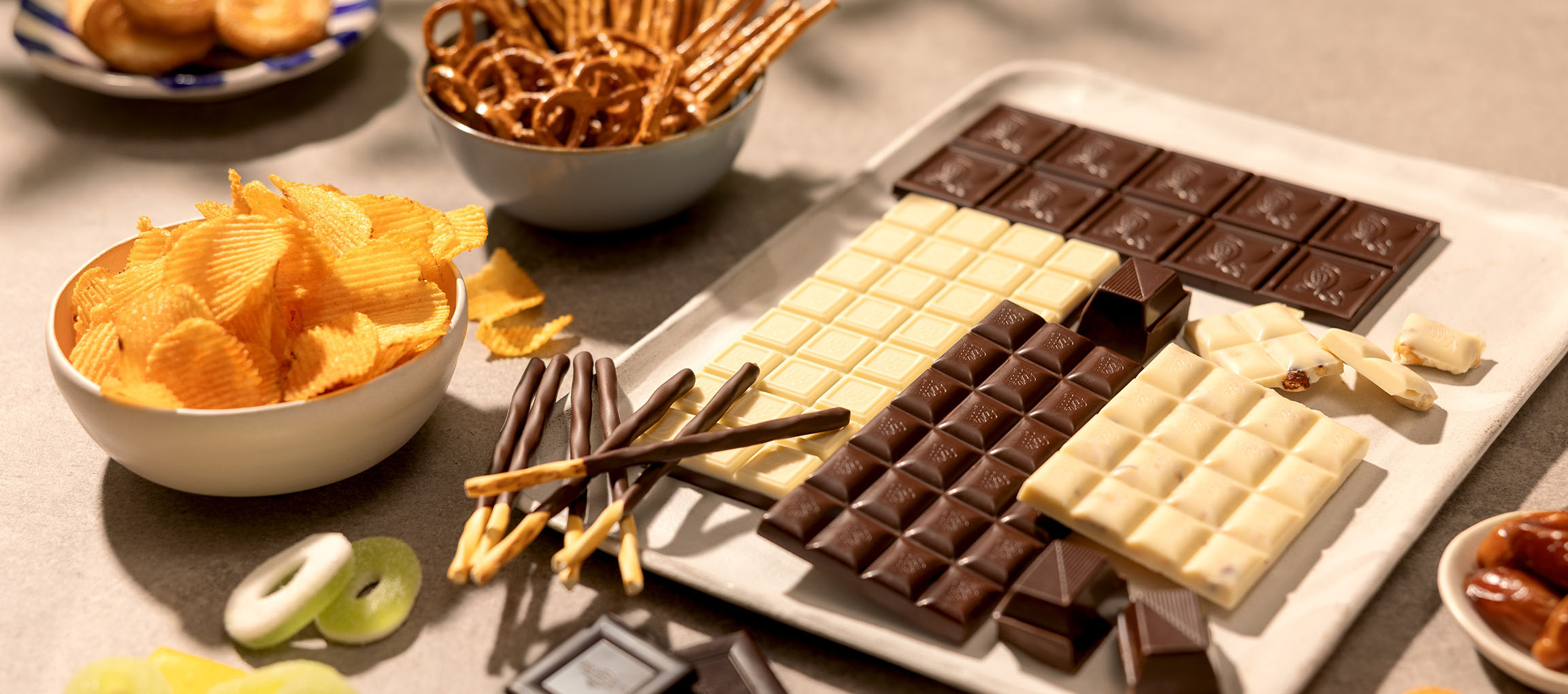Assorterade choklader, potatischips, kringlor och godis på ett bord.