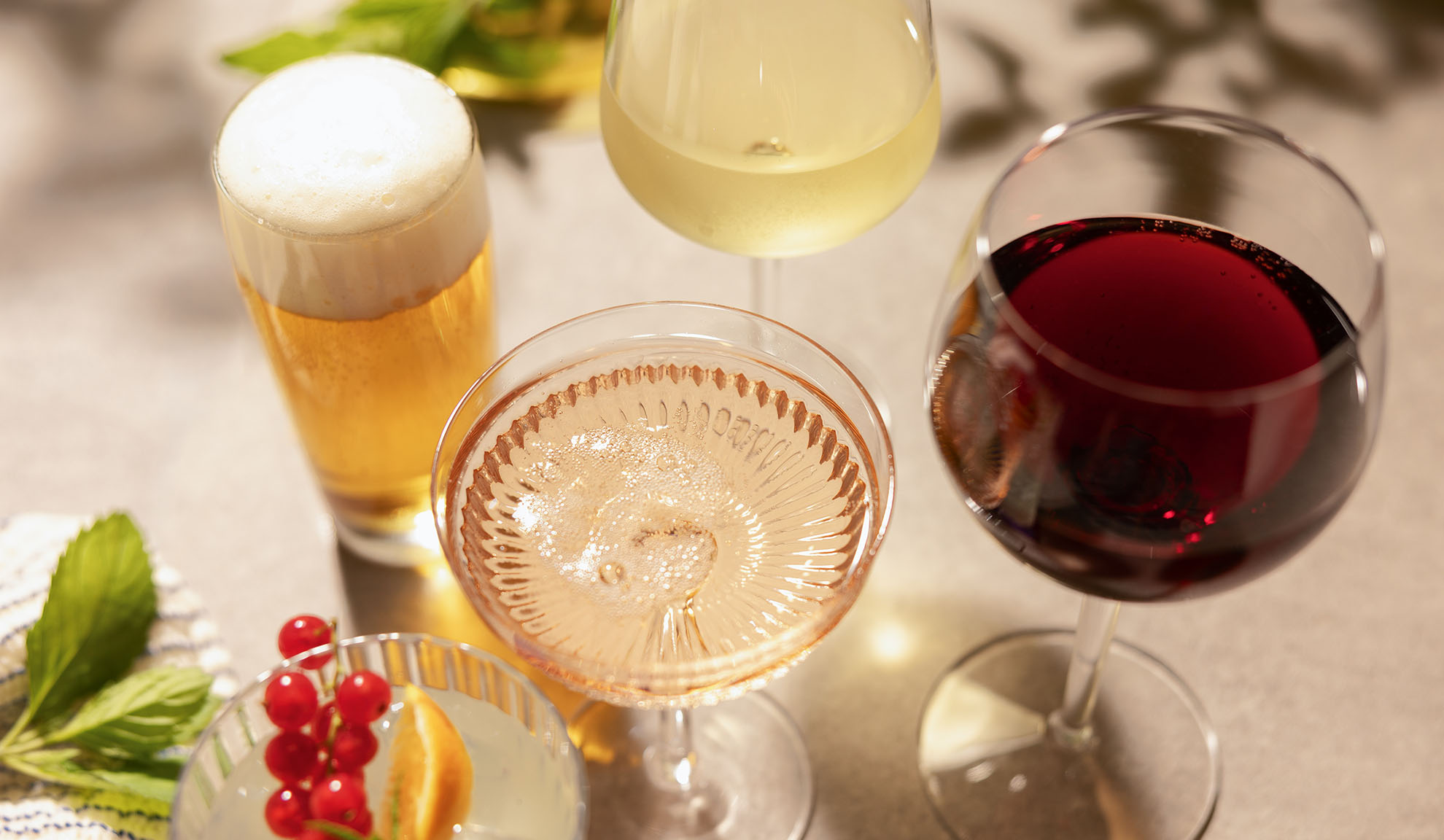 Glas med öl, vitt, rosé och rött vin, med en cocktail och bär.