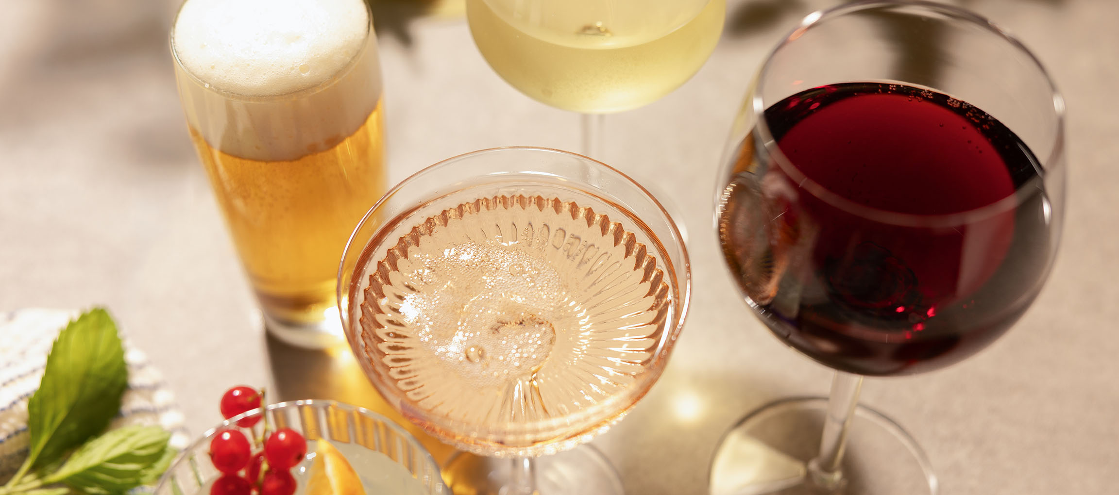 Öl, rosévin och rödvin i glas, med bär och mynta.