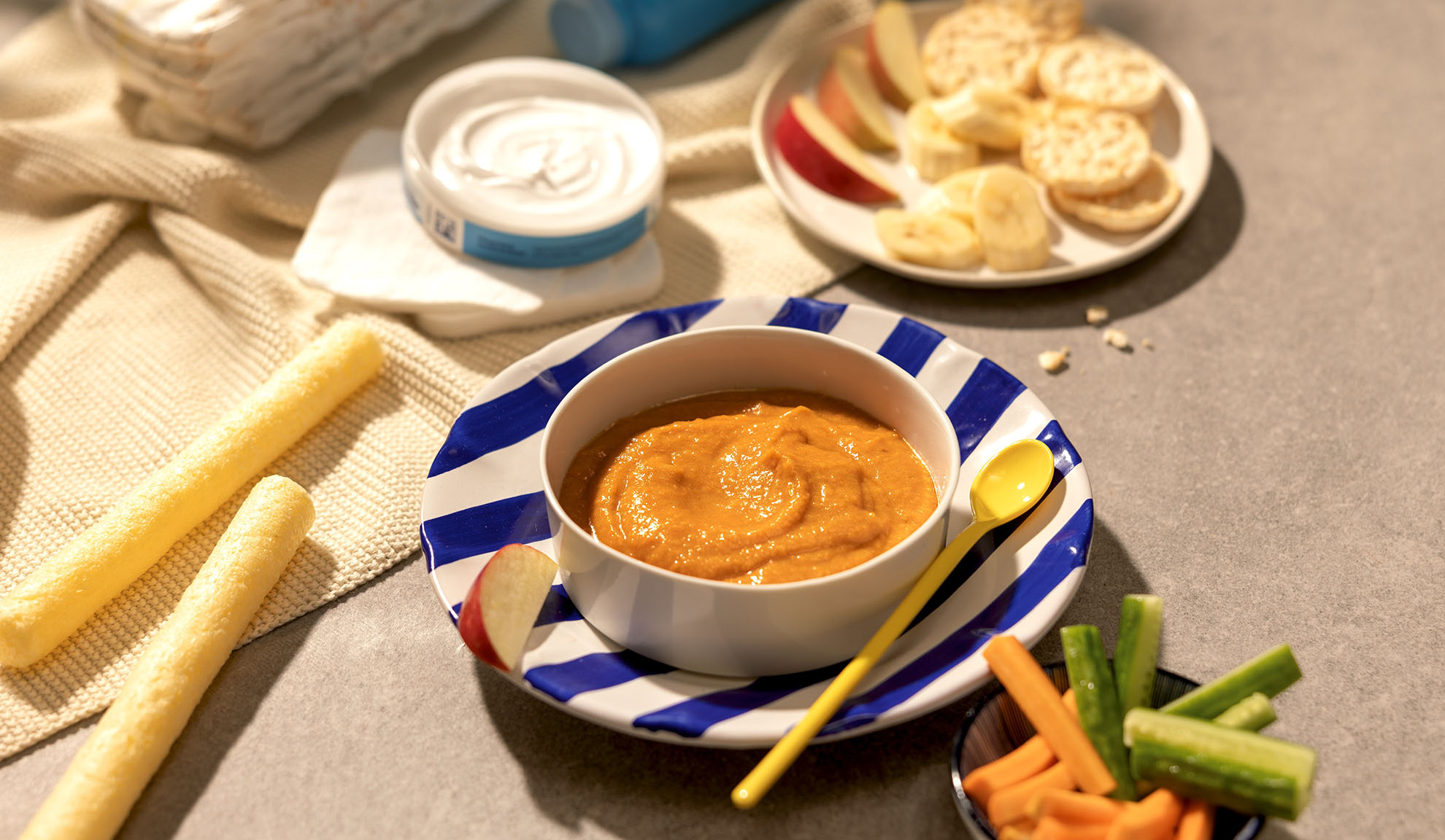 Barnmat: skål med puré, frukt, pinnar och grönsaker på bordet.
