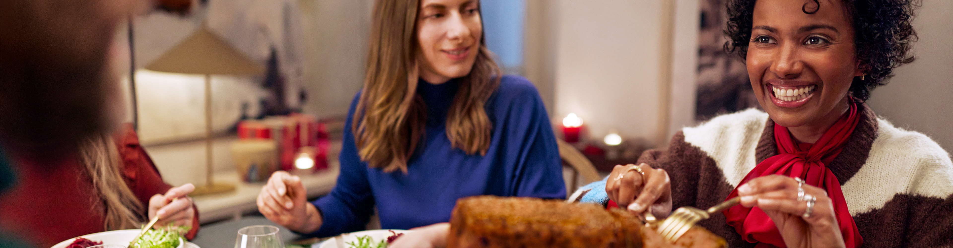 Vänner som äter middag tillsammans, med en brödlimpa i förgrunden.
