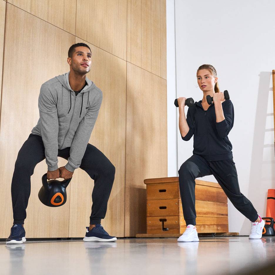 Man och kvinna i träningskläder, tränar med kettlebell och hantlar.