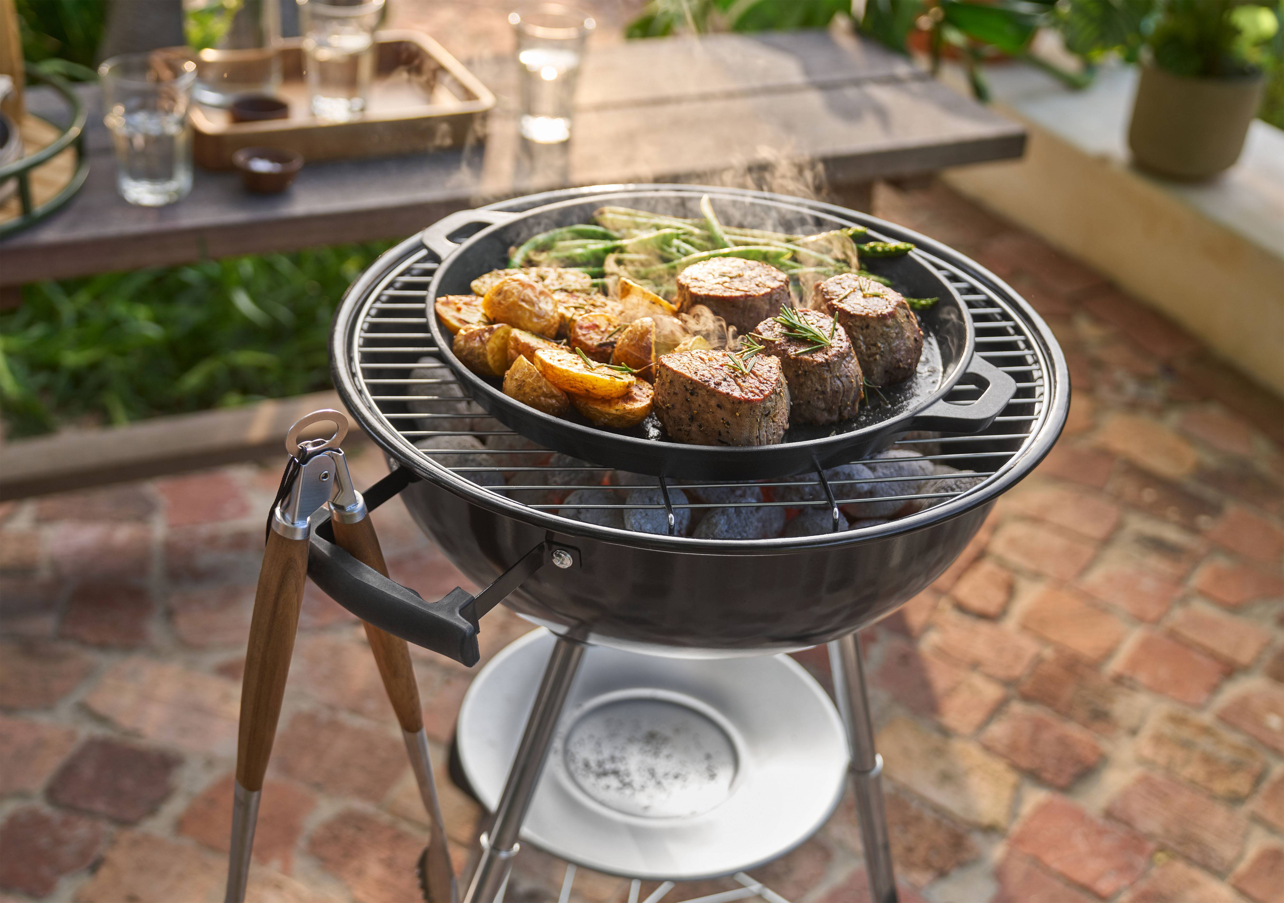 Grill med kött, potatis och gröna bönor som tillagas i en panna utomhus.