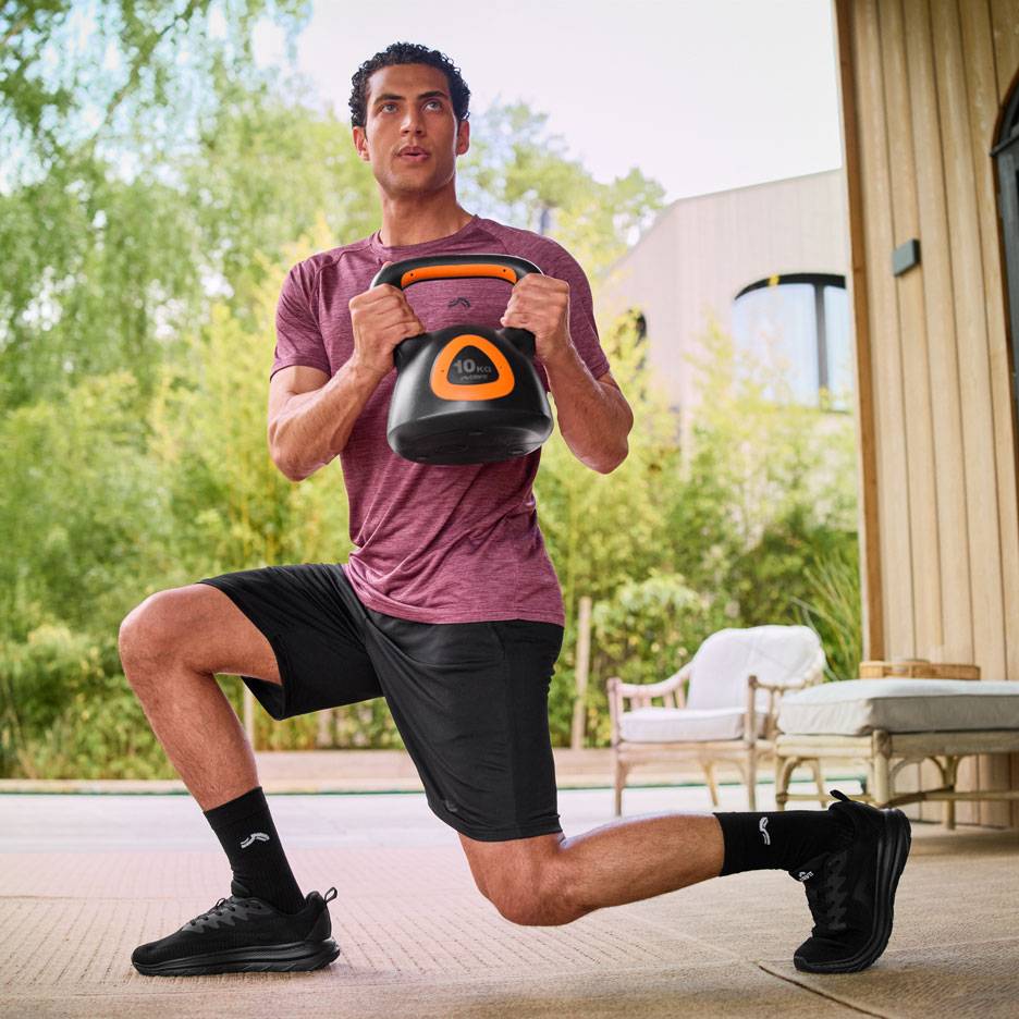 Man utför utfall med en 10 kg kettlebell utomhus.