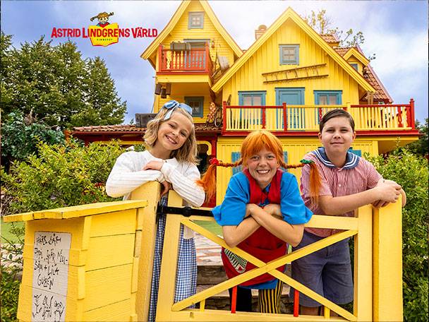Tre barn i Pippi Långstrump-kostymer framför ett gult hus på Astrid Lindgrens Värld.