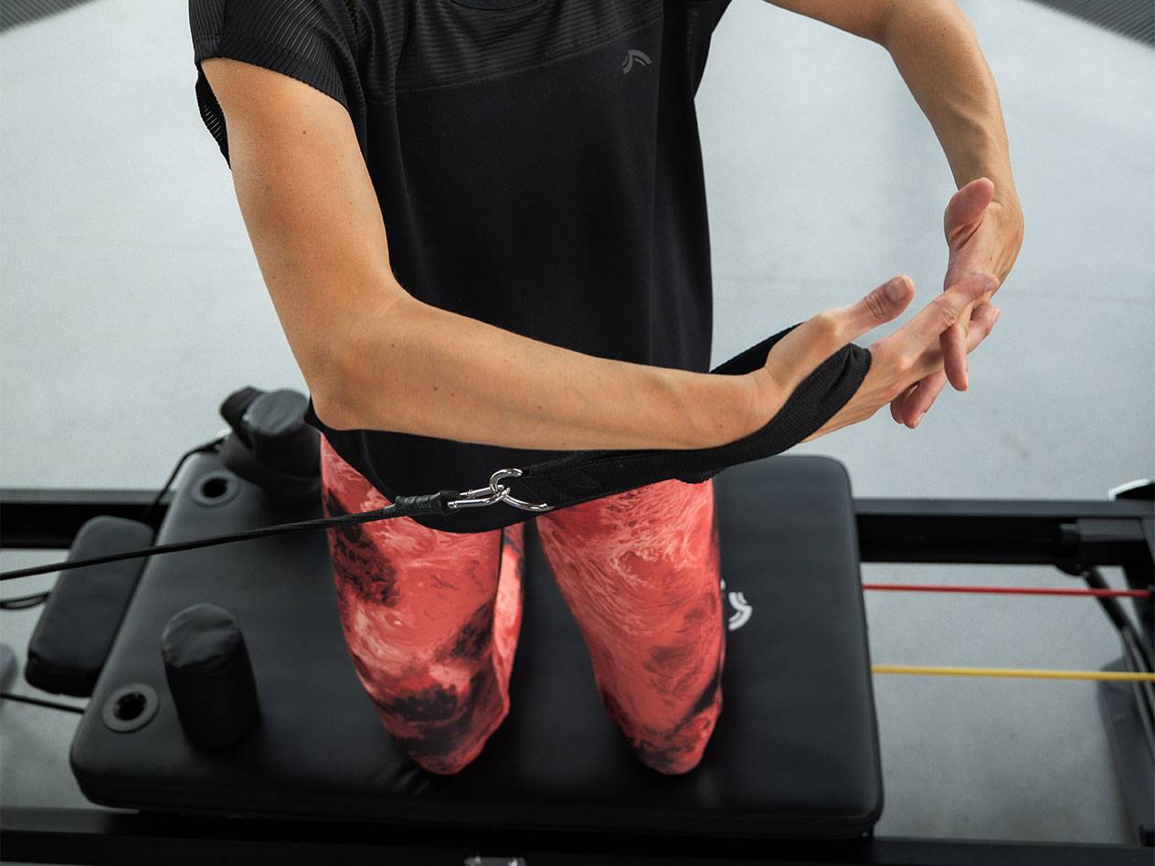 Kvinna tränar med motståndsband på en pilatesmaskin.