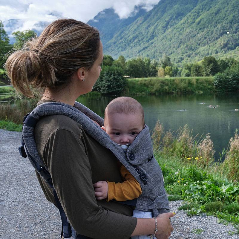 Mamma med bebis i bärsele utomhus.