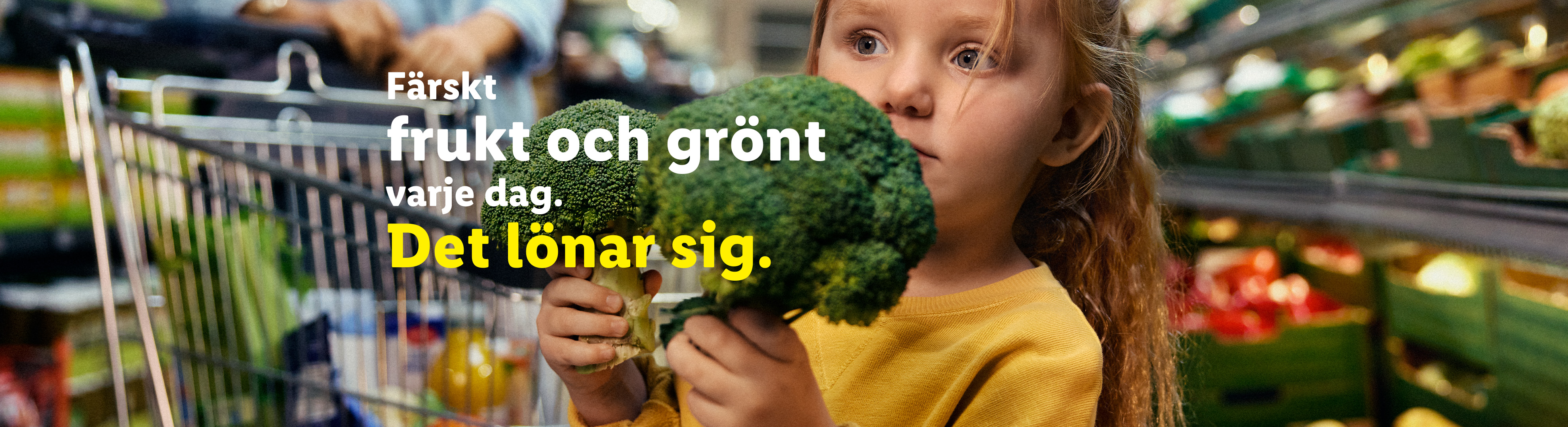 Ett barn håller i broccoli i en mataffär med texten 'Färskt frukt och grönt varje dag. Det lönar sig.'