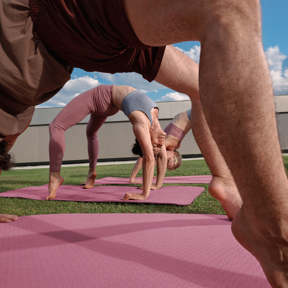 Människor som yogar utomhus på yogamattor, klädda i träningskläder.