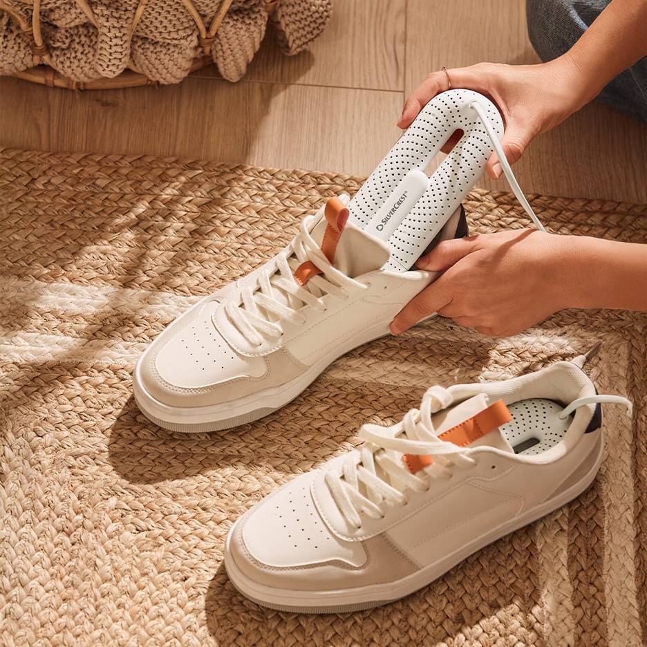 Silvercrest skotork i vita sneakers på en flätad matta.