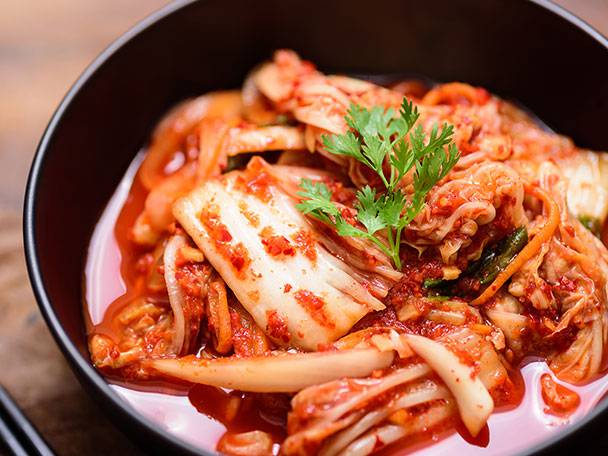 En skål med kimchi, garnerad med färsk koriander.