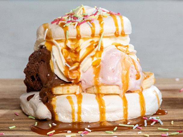 Marängdessert med glass, banan, kolasås och strössel.