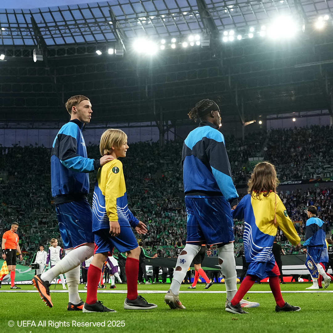 Fotbollsspelare och barn går på planen på en fullsatt arena.
