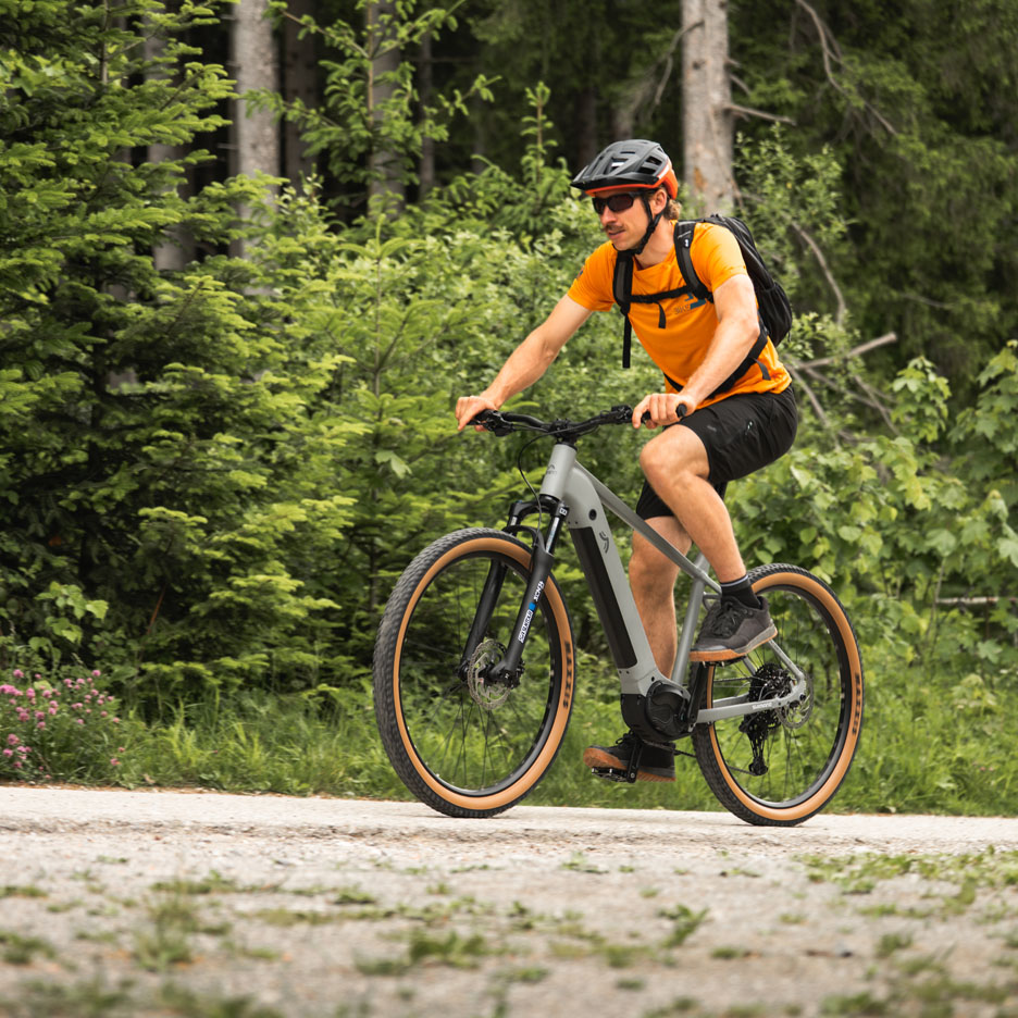 Man cyklar elcykel på skogsväg.