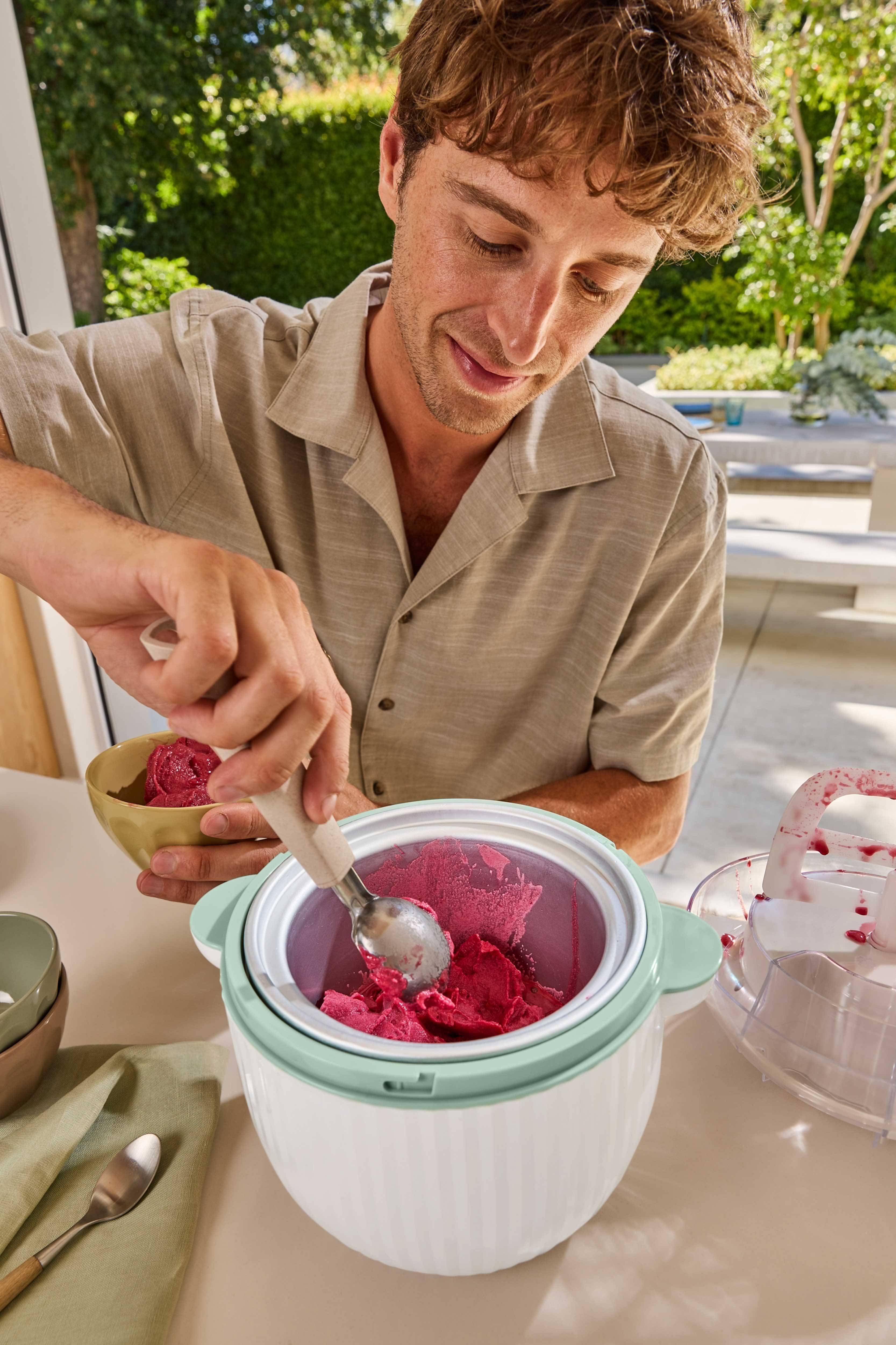 Man skopar röd sorbet från en glassmaskin till en skål.