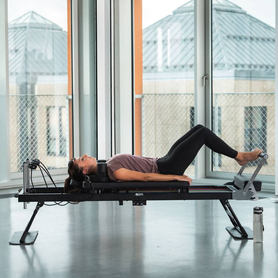 Kvinna som tränar Pilates på en reformer-maskin.