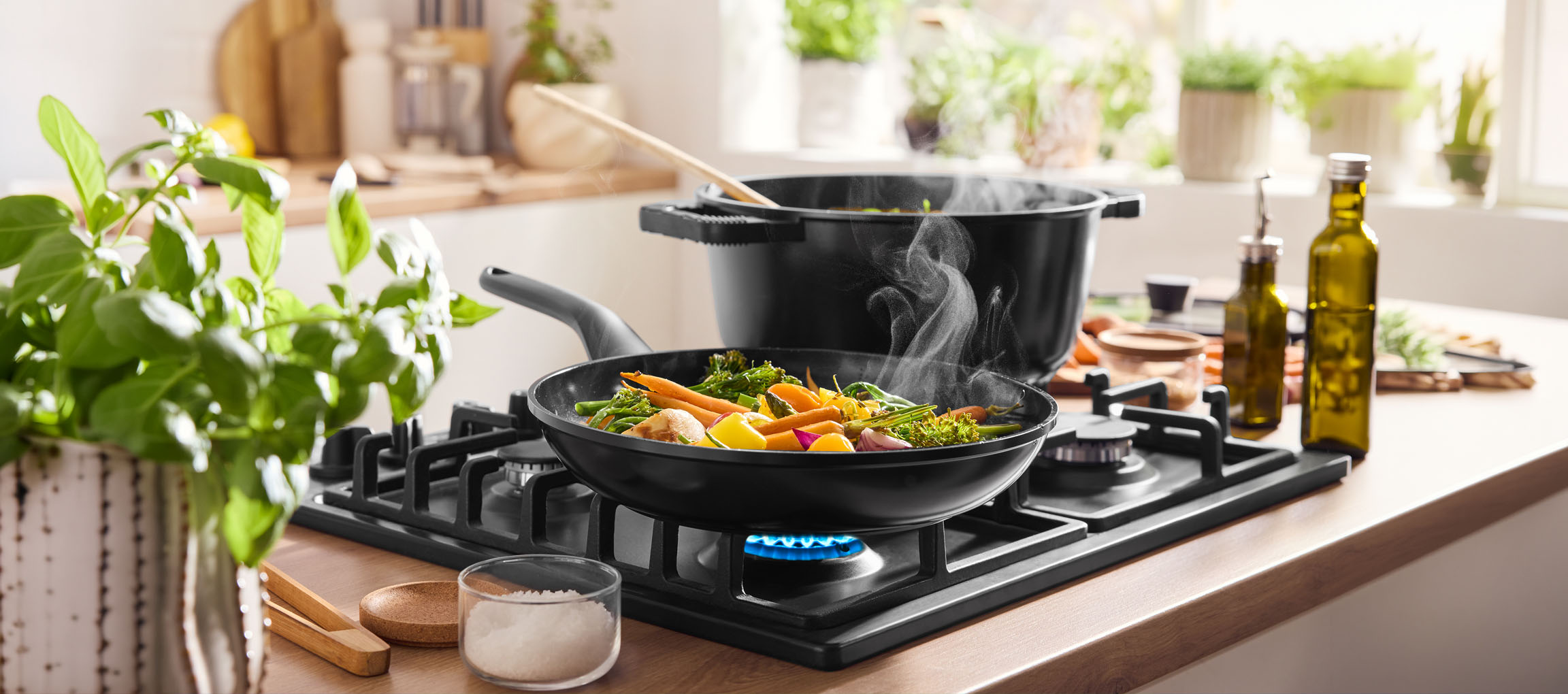 Matlagning av grönsaker i en panna på en gashäll, med en kastrull och olivolja i närheten.