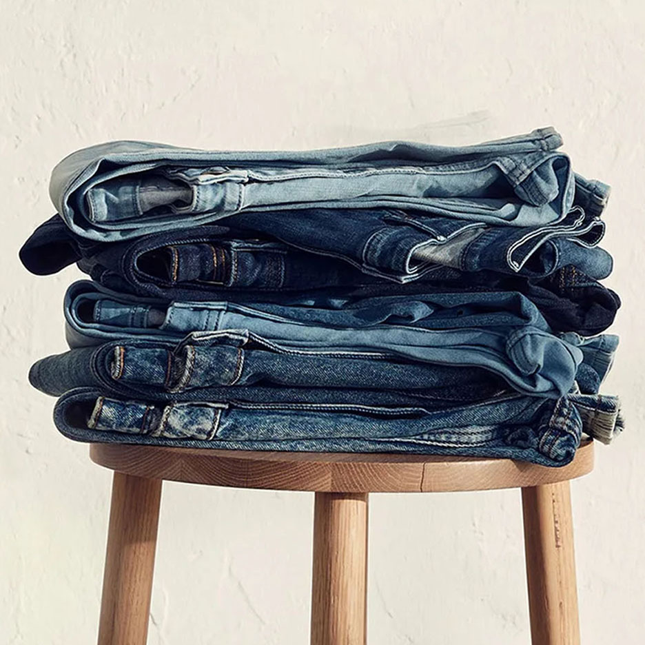En hög med jeans i olika blå nyanser på en träpall.