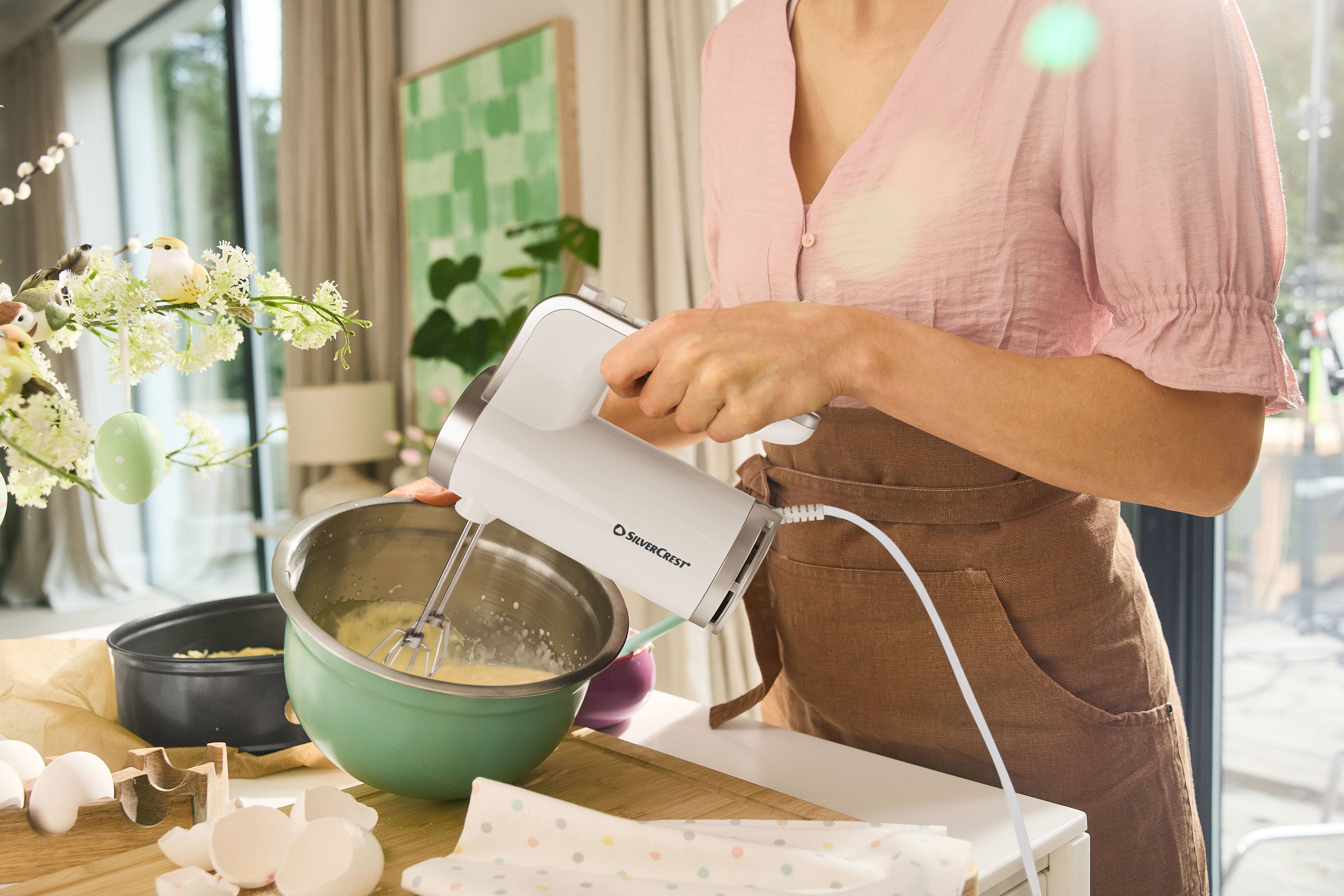 Kvinna använder en SilverCrest handmixer för att blanda ingredienser i en skål.
