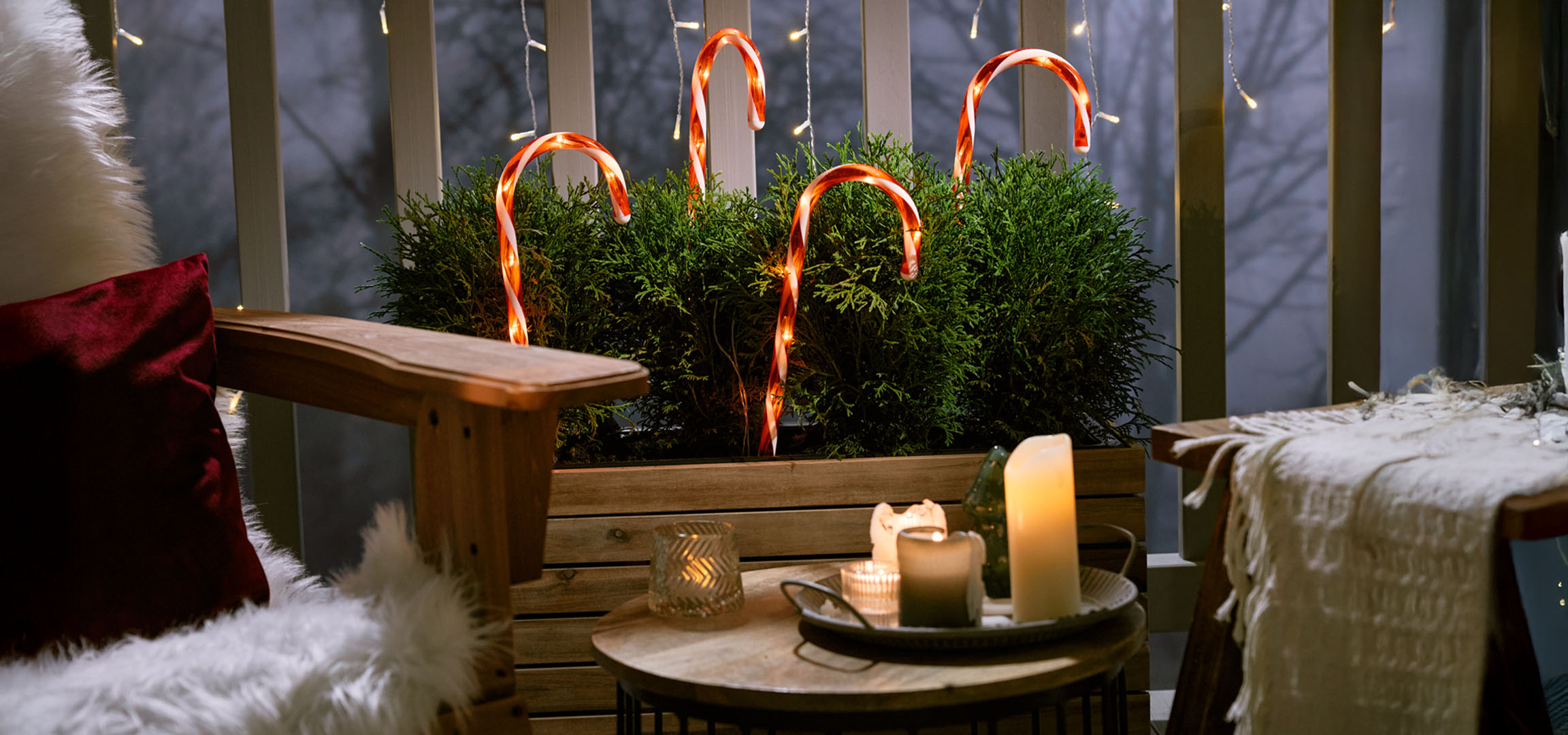 Juldekorerad balkong med en stol, ljus och godisrottingar.