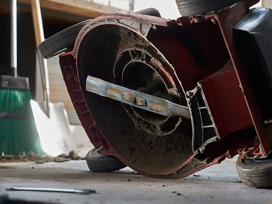 Smutsig gräsklippare upp och ner, med synligt blad