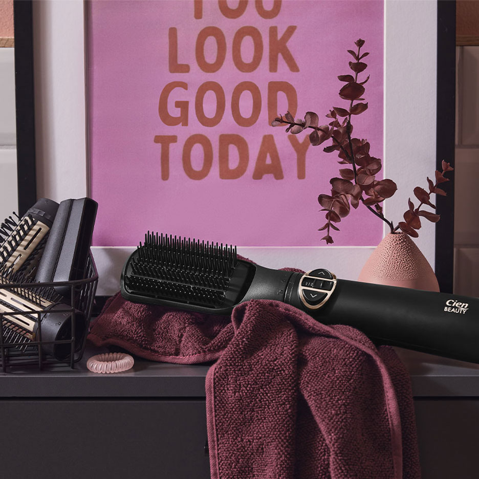 Cien Beauty plattborste på en handduk, med håraccessoarer och en affisch.