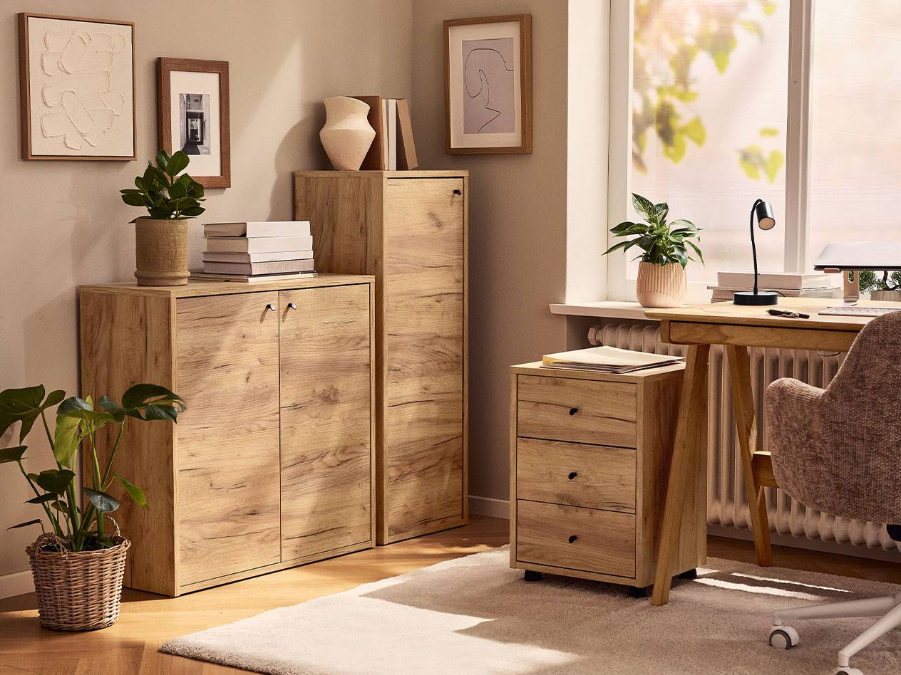 Ett hemmakontor med ljusa träskåp, en skrivbordsstol och en skrivbordslampa.