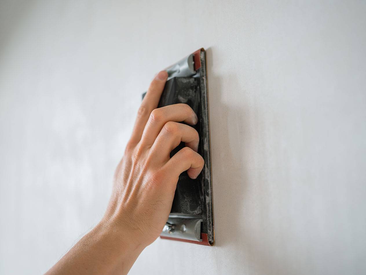 Hand slipar en vägg med ett slipblock