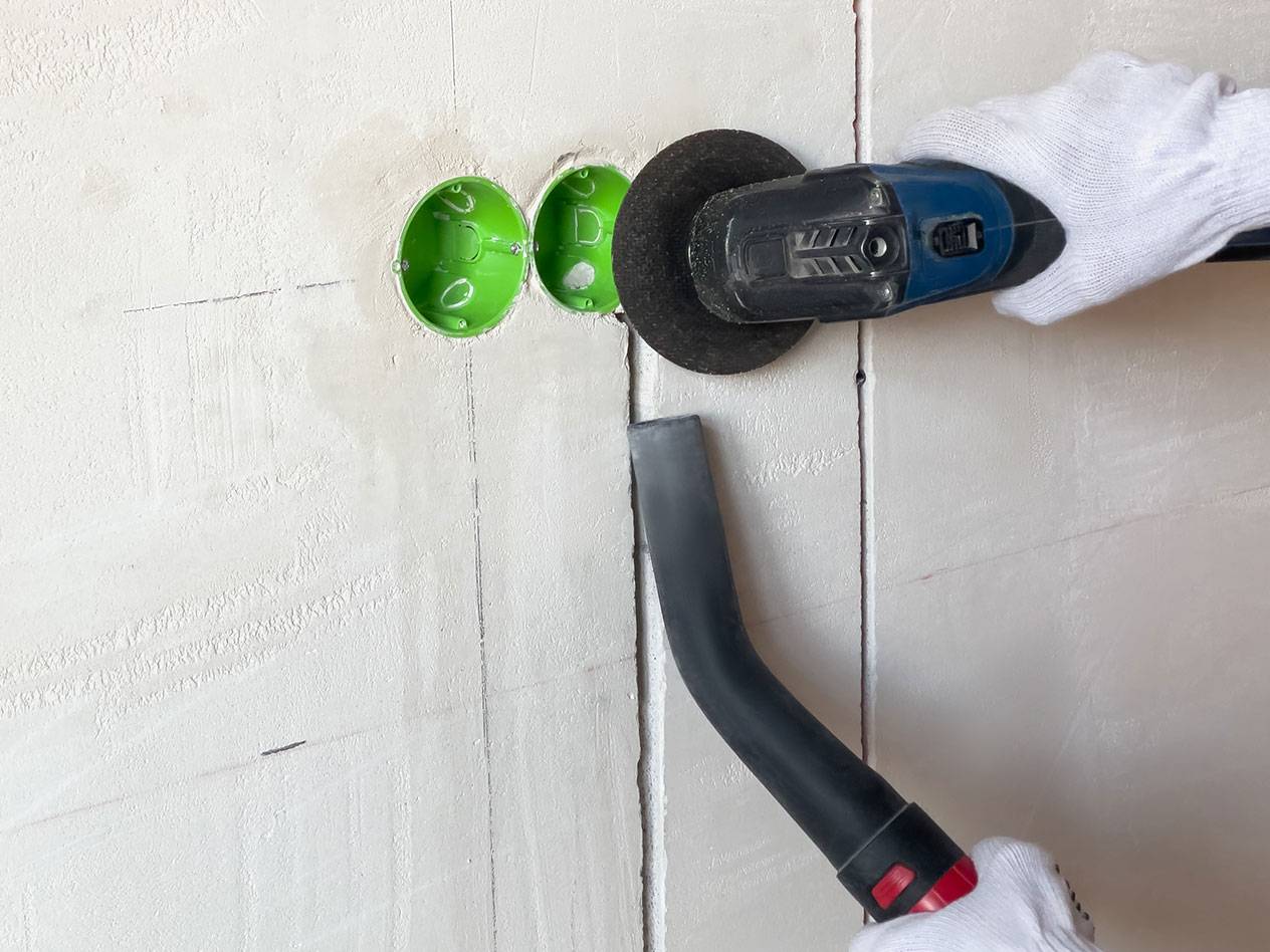 Elverktyg skär spår i en vägg med en dammsugare för damm.