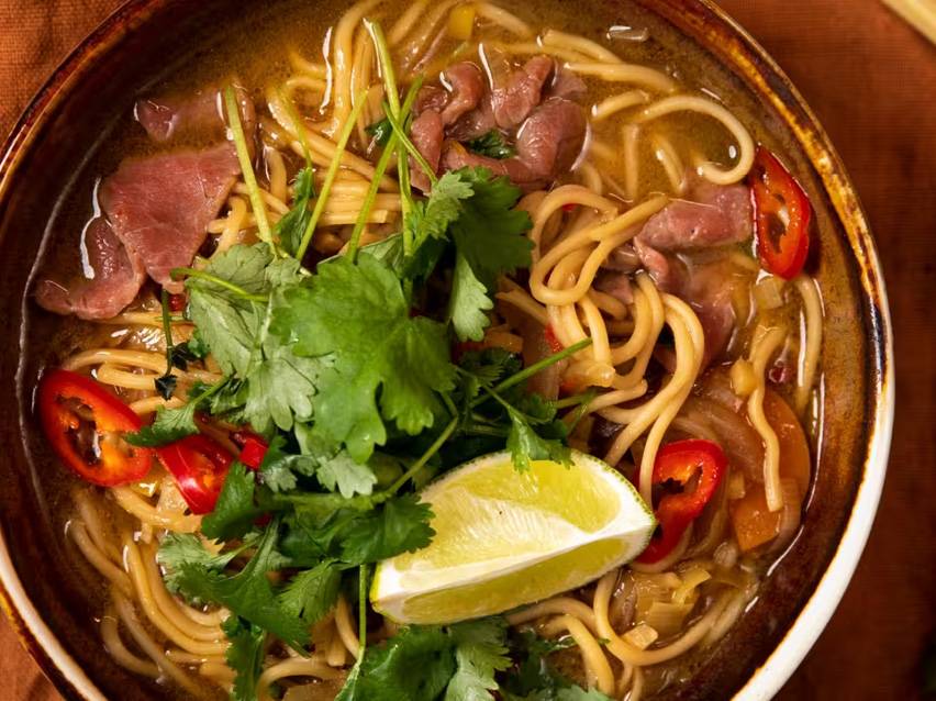 Nudelsoppa med nötkött, chili, koriander och lime i en skål.