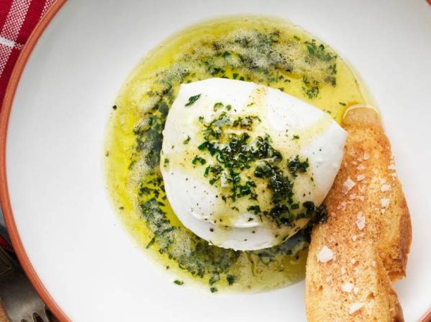 En tallrik med mozzarella, olivolja, örter och bröd.