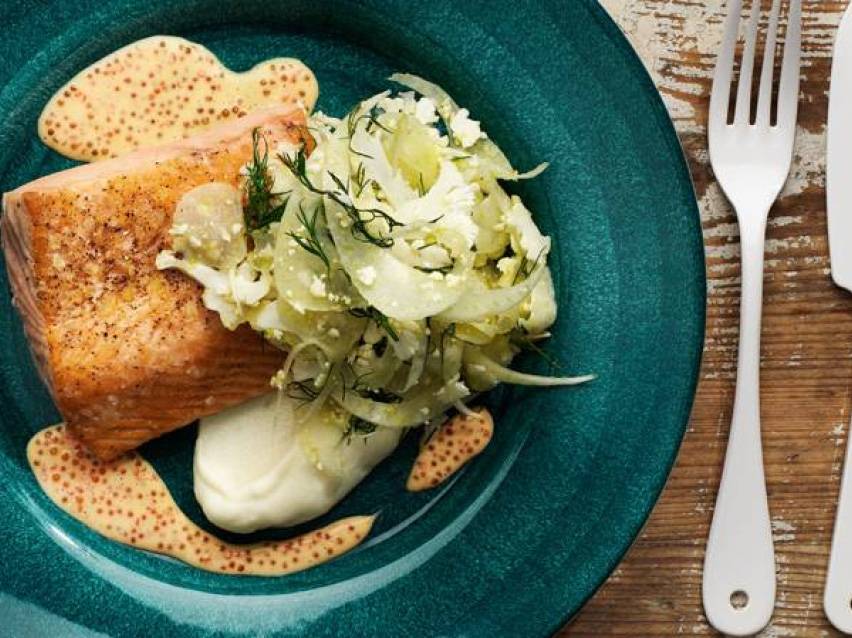 Laxfilé med fänkålssallad, potatispuré och senapssås på en turkos tallrik.