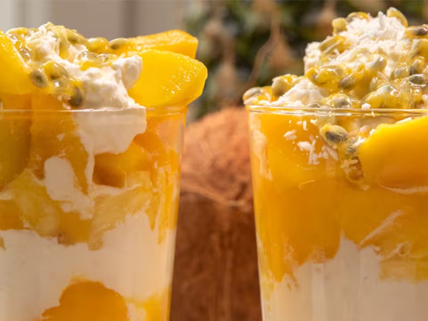 Två glas fyllda med krämig mangodessert toppad med passionsfrukt.