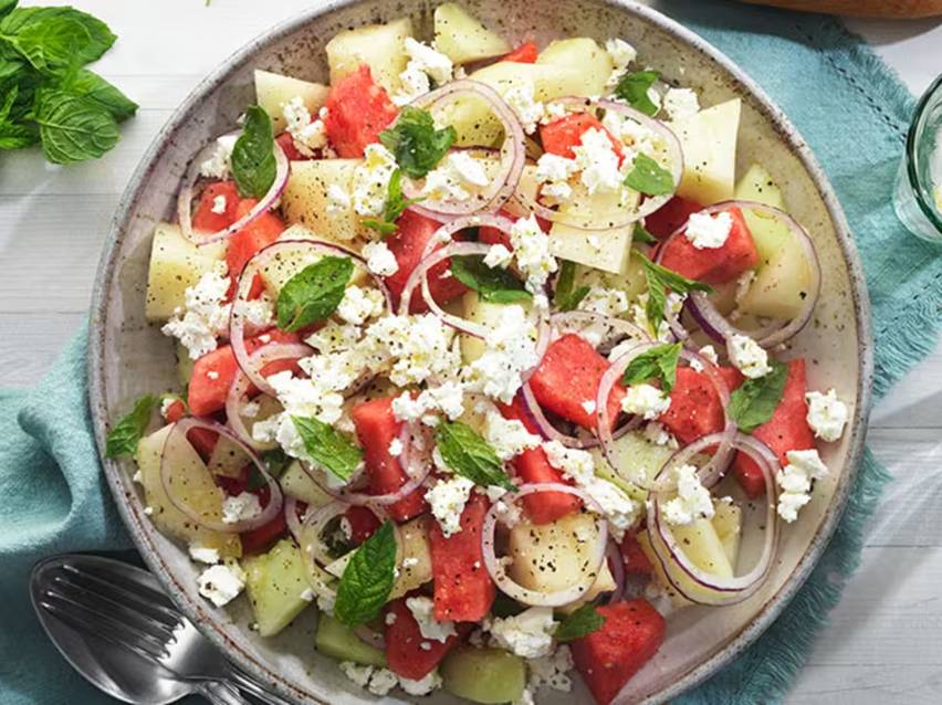 Vattenmelon- och fetaostsallad med rödlök och mynta i en skål.