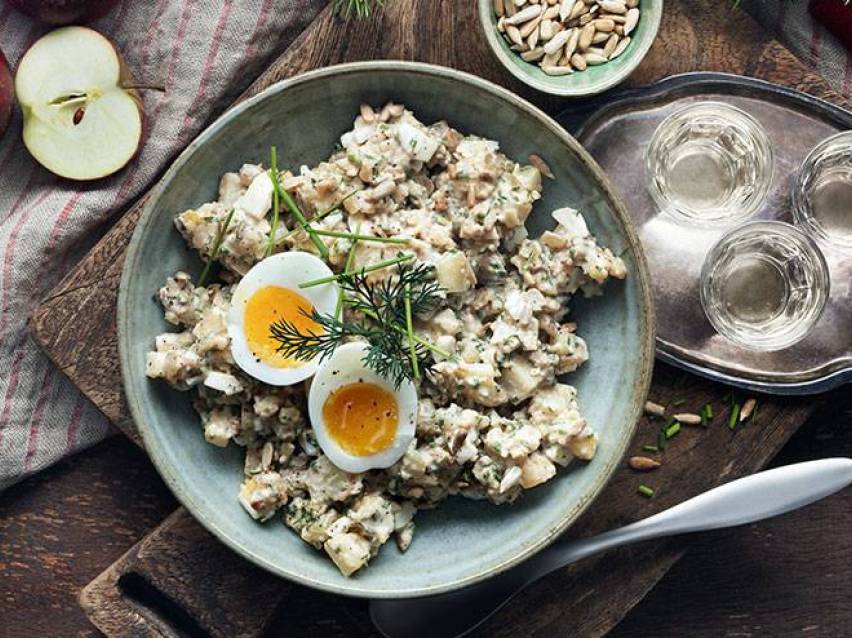 Potatissallad med ägg, dill och gräslök, serverad med äpplen och solrosfrön.