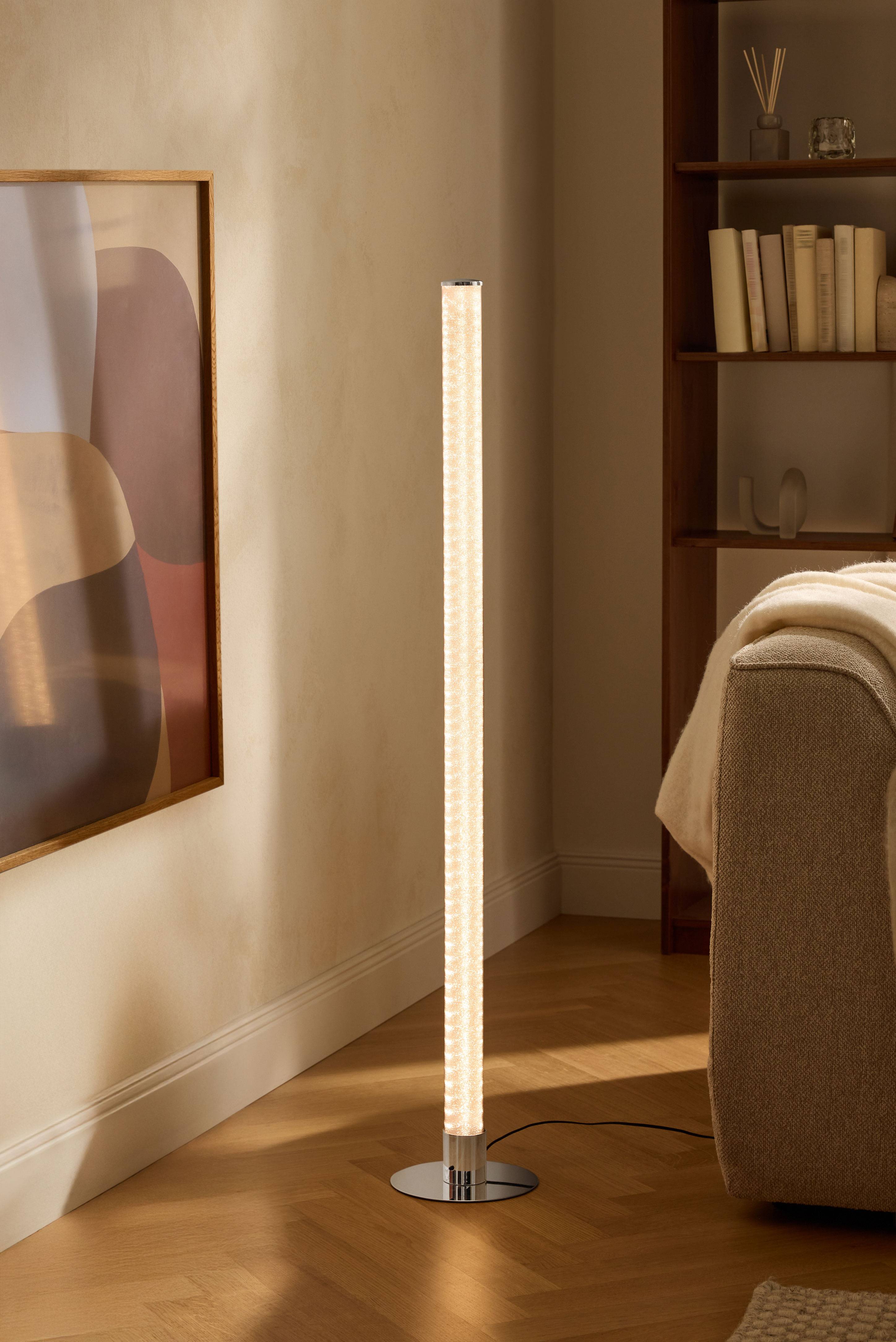 Modern golvlampa i vardagsrum med bokhylla och soffa.