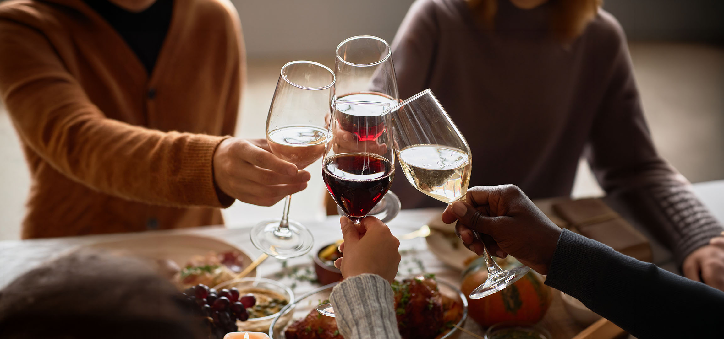 Människor skålar med glas rött och vitt vin.